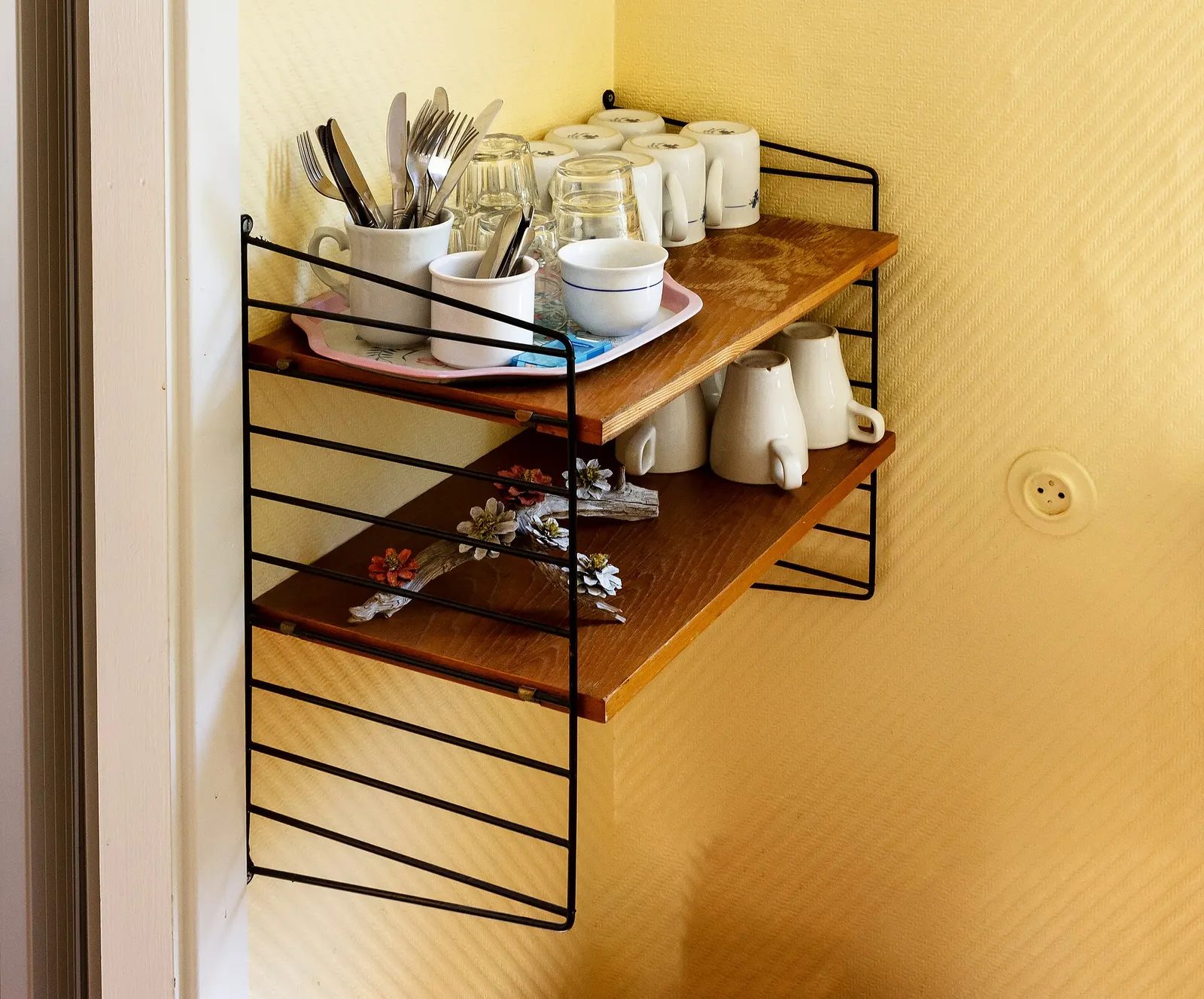 Cups, glasses and flatware on a String shelf. Interior of Brastad Bageri, the local bakery in Brastad, Lysekil Municipality, Sweden.